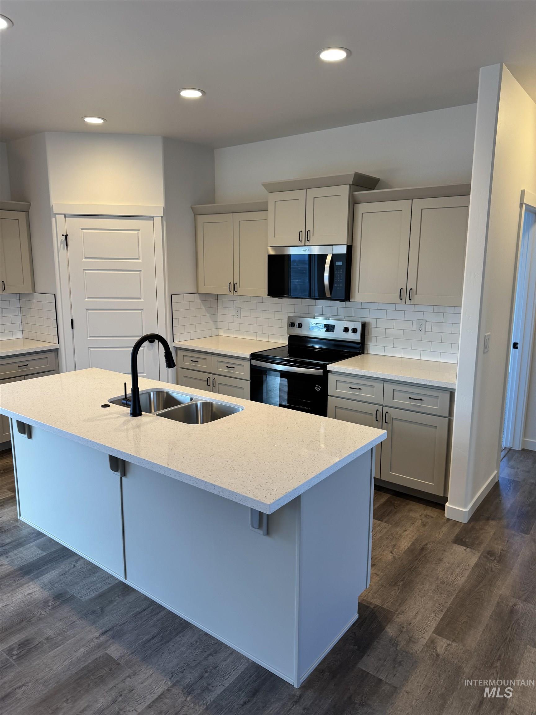 2008 Harrison Street South Twin Falls, ID 83301 - Photo 2 of 32 Kitchen featuring decorative backsplash, stainless steel appliances, light stone counters, dark wood-type flooring, and recessed lighting