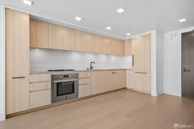 a view of empty room with kitchen and windows