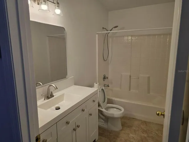 a bathroom with a granite countertop sink a toilet and shower