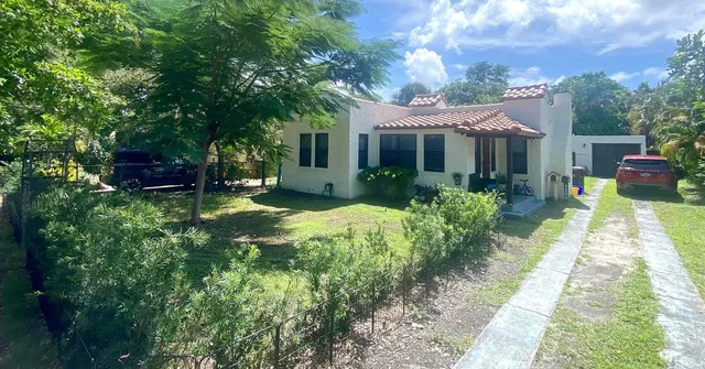 a view of a house with a big yard potted plants and large tree