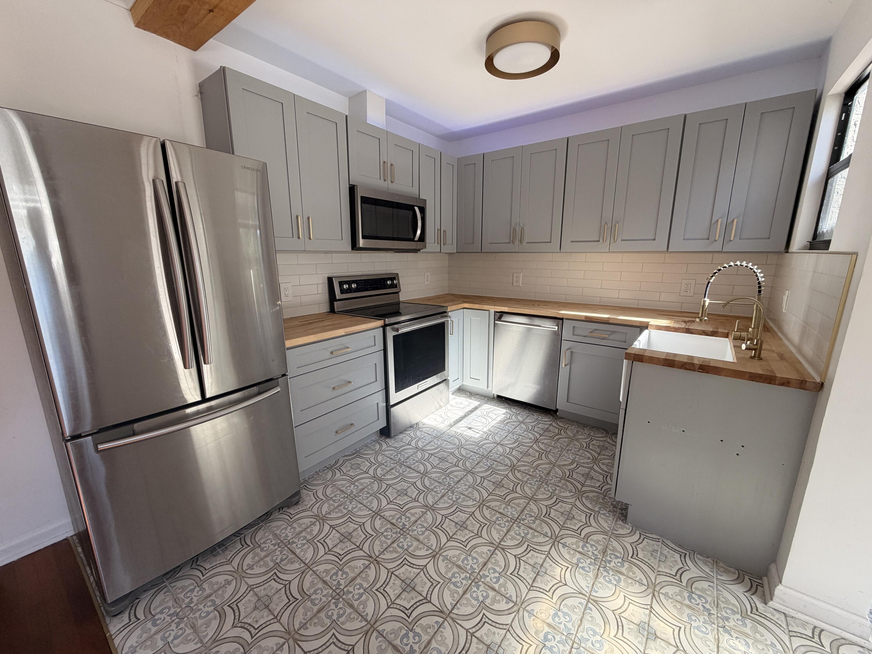 1026 Upland Road, Unit MAIN HOUSE West Palm Beach, FL 33401 - Photo 6 of 11 a kitchen with stainless steel appliances granite countertop a refrigerator stove a sink dishwasher and microwave