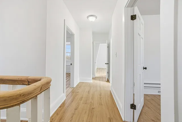 a view of a hallway with wooden floor and staircase