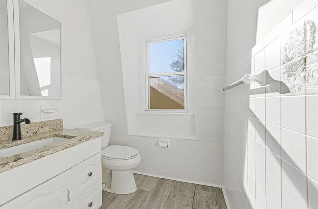 a bathroom with a granite countertop toilet sink and mirror