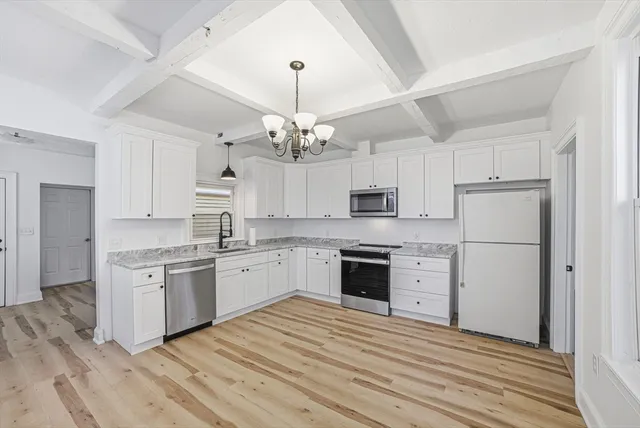 a large kitchen with cabinets wooden floor and stainless steel appliances