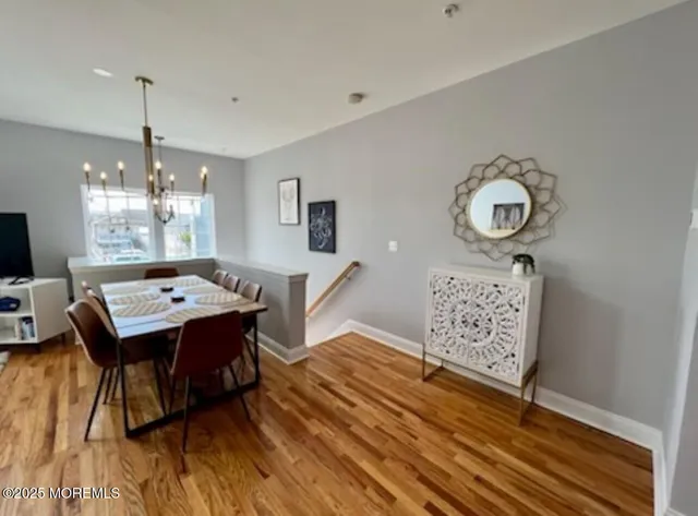 a dining room with wooden floor a chandelier a wooden table and chairs