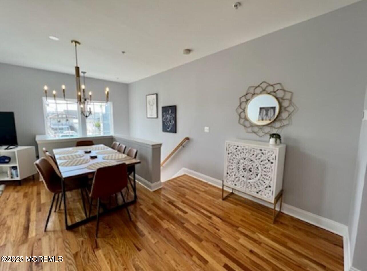 15 Sumner Avenue, Unit 11 Seaside Heights, NJ 08751 - Photo 2 of 13 a dining room with wooden floor a chandelier a wooden table and chairs
