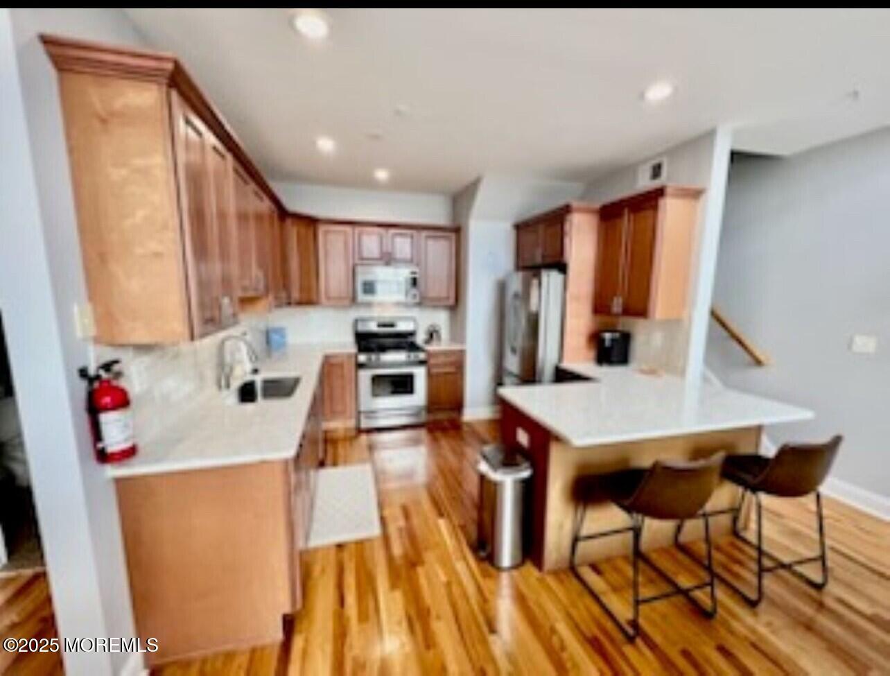 15 Sumner Avenue, Unit 11 Seaside Heights, NJ 08751 - Photo 5 of 13 a kitchen that has a microwave a stove and wooden floor