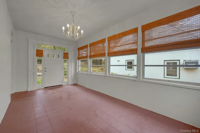 a view of an empty room with chandelier and a window