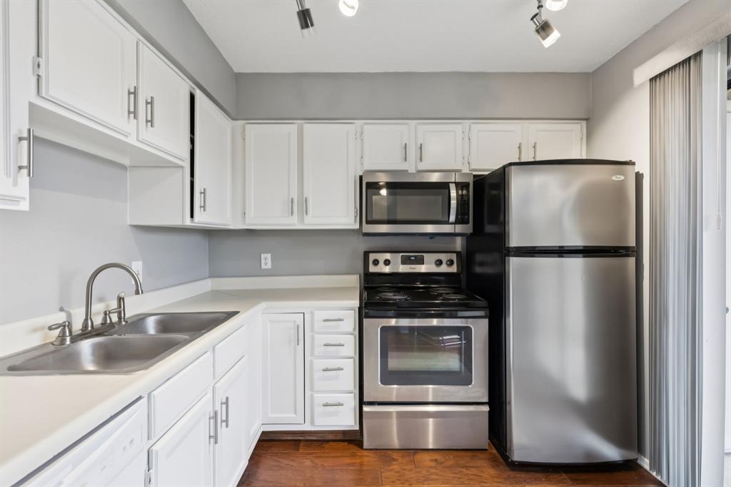 4748 Old Bent Tree Lane, Unit 1808 Dallas, TX 75287 - Photo 6 of 28 a kitchen with cabinets stainless steel appliances and wooden floor