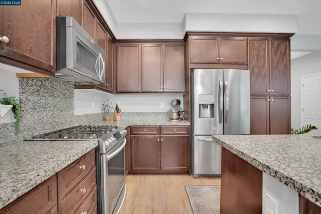 a kitchen with stainless steel appliances granite countertop a sink stove and refrigerator