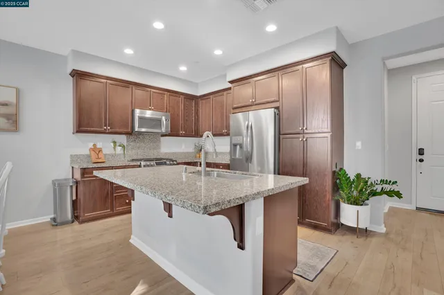 a kitchen with stainless steel appliances granite countertop a refrigerator a sink a stove and a refrigerator