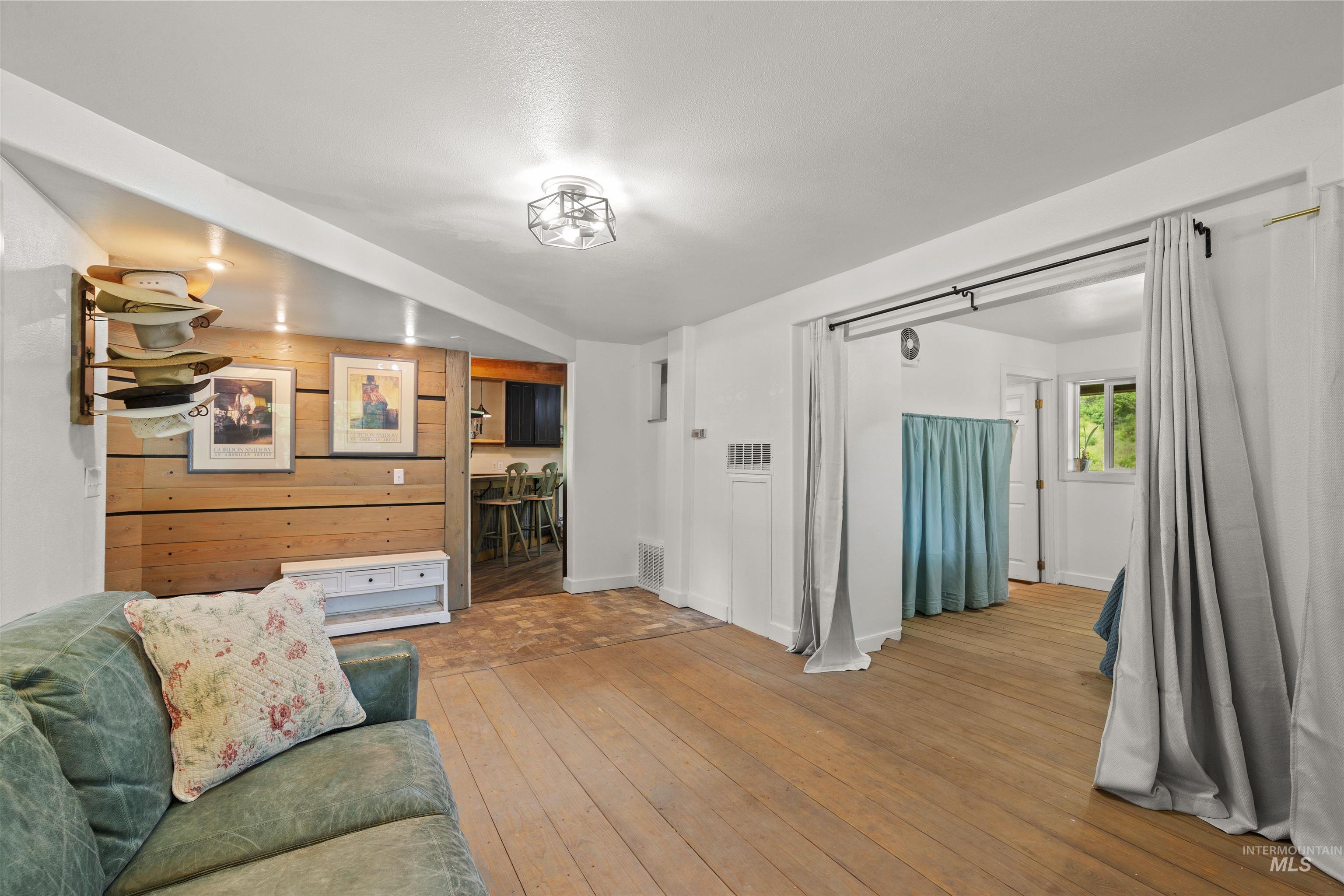 1314 Cedar Ridge Road Kendrick, ID 83537 - Photo 12 of 50 Open concept living space featuring wood-finish flooring, a wood-paneled accent wall, and a flush-mount ceiling light fixture