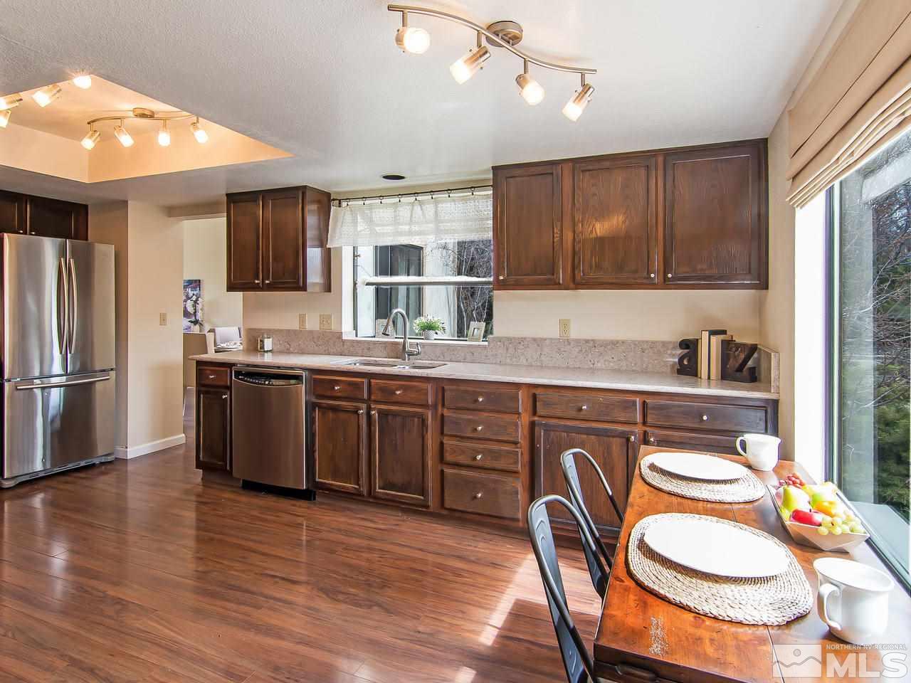 5302 Vista Ridge Way Reno, NV 89523 - Photo 7 of 20 a kitchen with stainless steel appliances granite countertop a sink a stove a refrigerator cabinets and a dining table with wooden floor