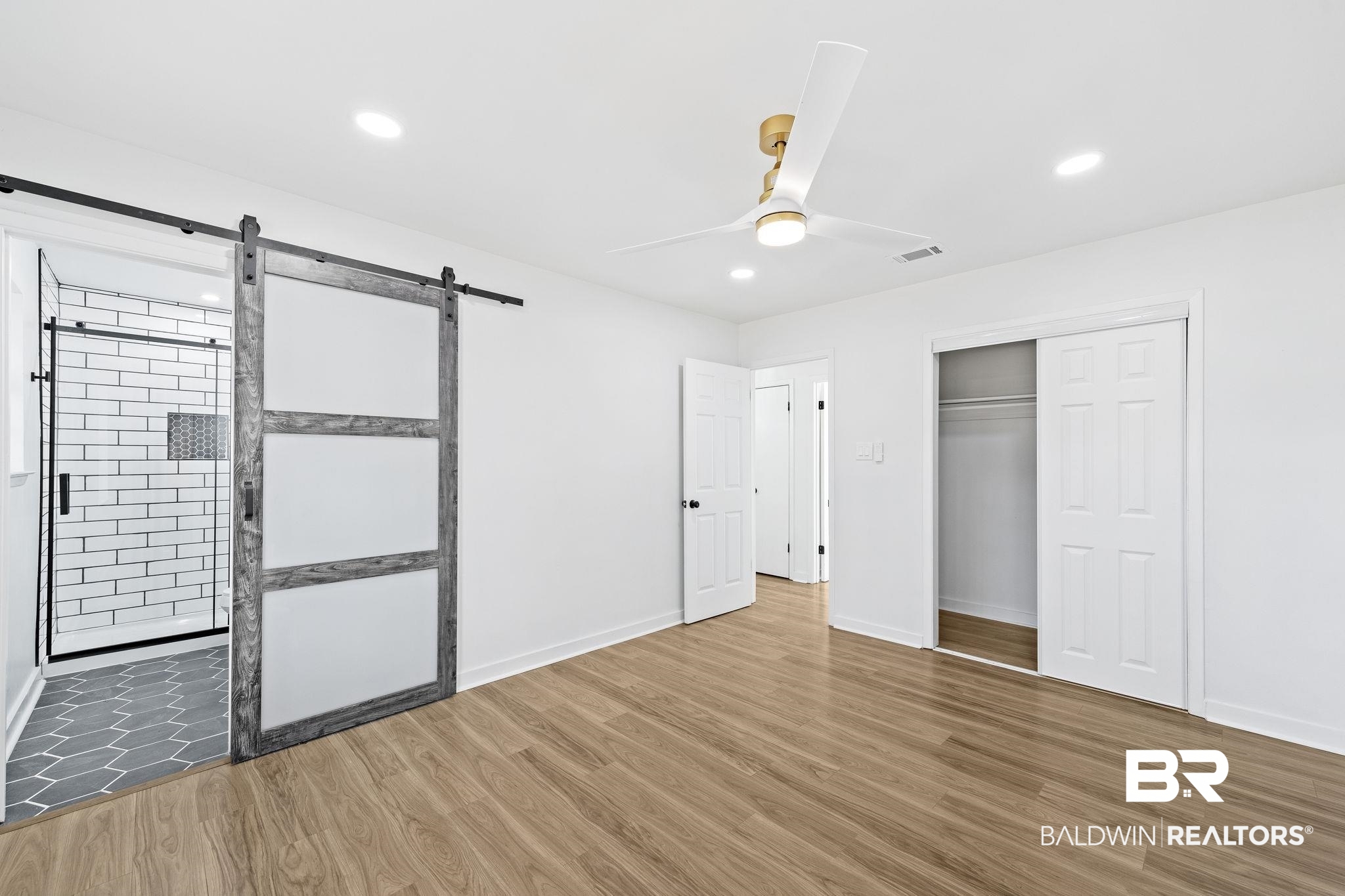 5398 Quail Run North Theodore, AL 36582 - Photo 21 of 46 Unfurnished bedroom featuring a barn door, ceiling fan, a closet, and hardwood / wood-style flooring