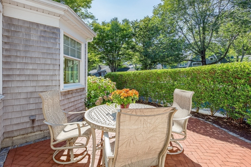 199 East Bay Road, Unit 13 Barnstable, MA 02655 - Photo 31 of 40 a view of a patio with table and chairs potted plants with wooden floor and fence