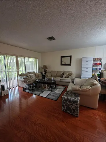 a living room with lots of furniture a lamp wooden floor and a large window