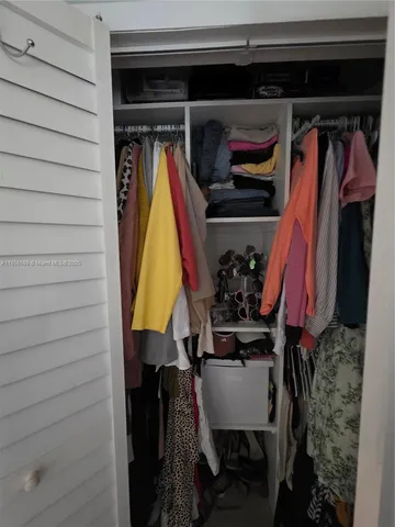a view of walk in closet with clothes and shoes