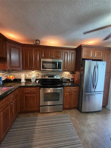 a kitchen with stainless steel appliances granite countertop a refrigerator stove and cabinets