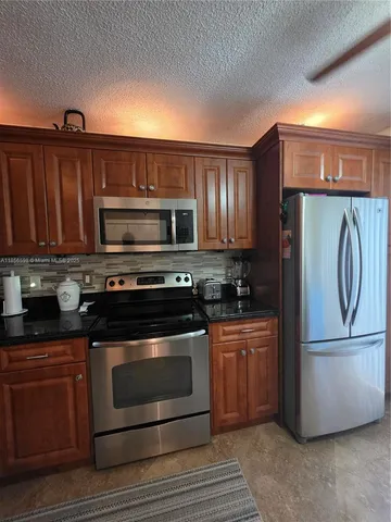a kitchen with granite countertop a refrigerator stove and microwave