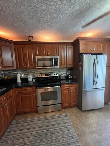 a kitchen with granite countertop a refrigerator stove and microwave
