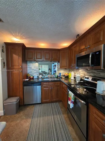 a kitchen with stainless steel appliances granite countertop a refrigerator stove and a sink