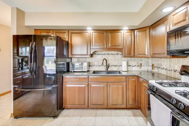 a kitchen with kitchen island granite countertop a sink counter top space appliances and a window