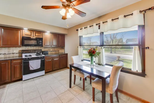 a kitchen with stainless steel appliances a table chairs and a refrigerator