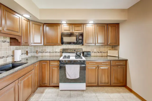 a kitchen with kitchen island granite countertop a sink stove and cabinets