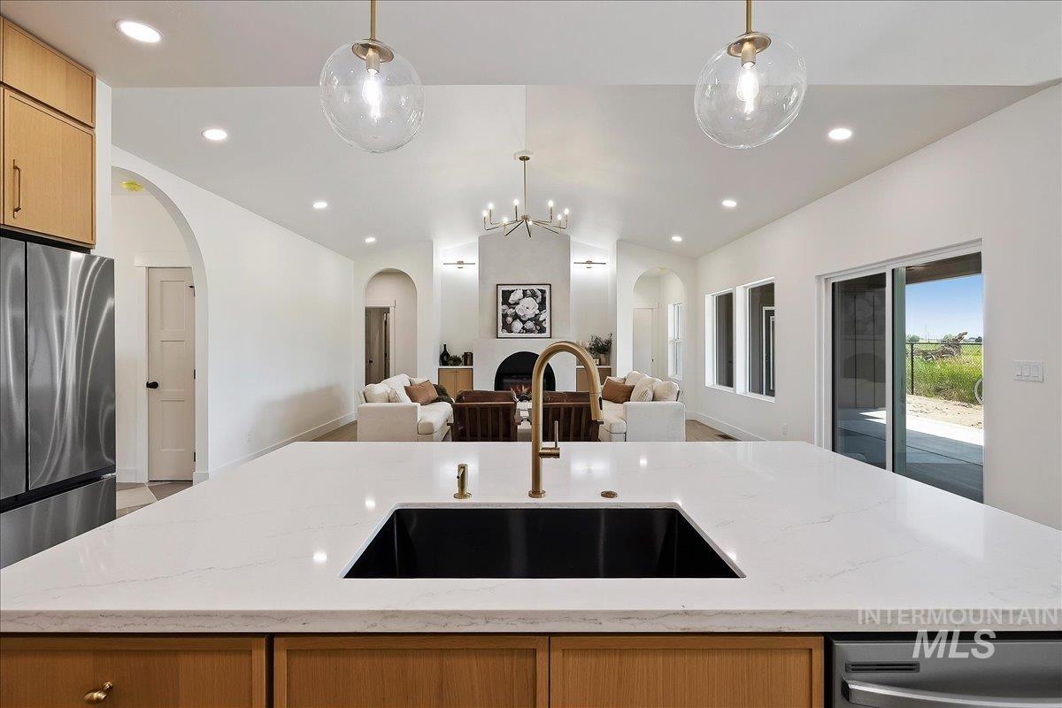 2005 Sparrow Street Rupert, ID 83350 - Photo 11 of 30 Kitchen island with a black undermount sink and brass faucet, featuring a white countertop and wood-finish cabinetry