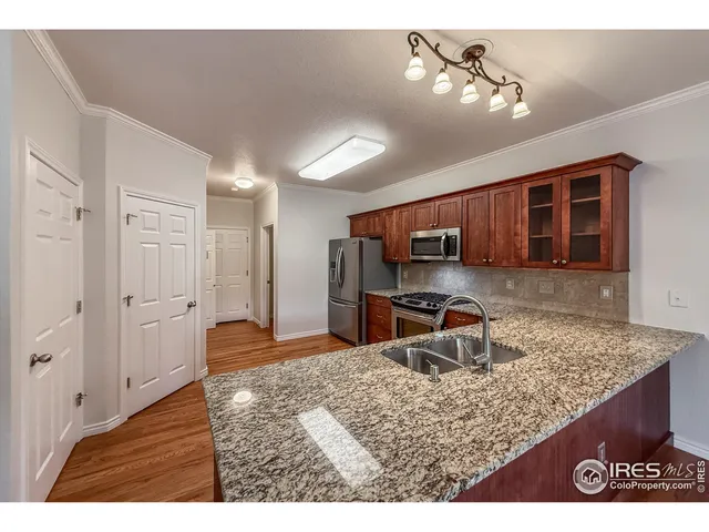 a kitchen with stainless steel appliances granite countertop a refrigerator a sink dishwasher a stove with wooden cabinets