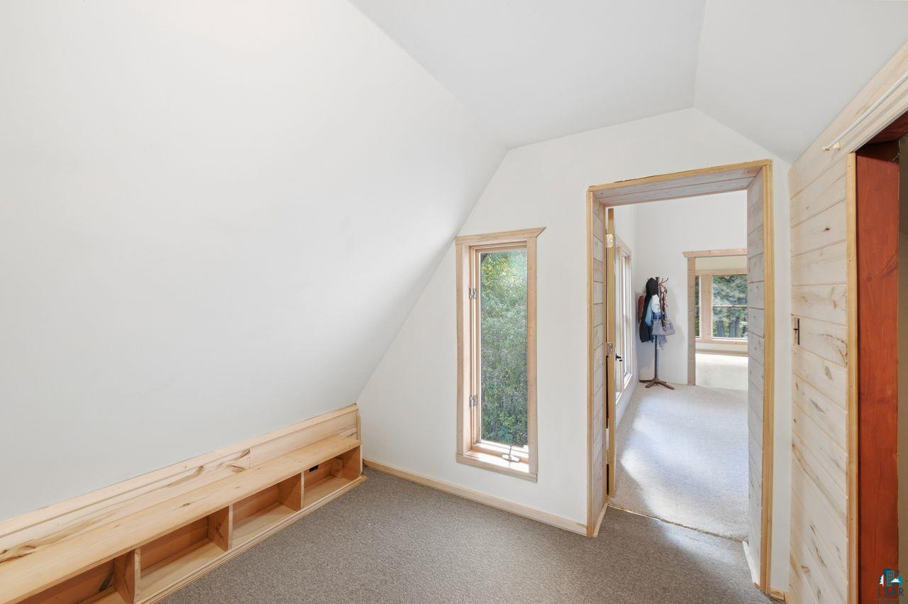65889 Old County Road Marengo, WI 54855 - Photo 15 of 44 Sloped ceiling with crisp white walls, built-in wooden shelving, wood-trimmed window, and neutral carpeting