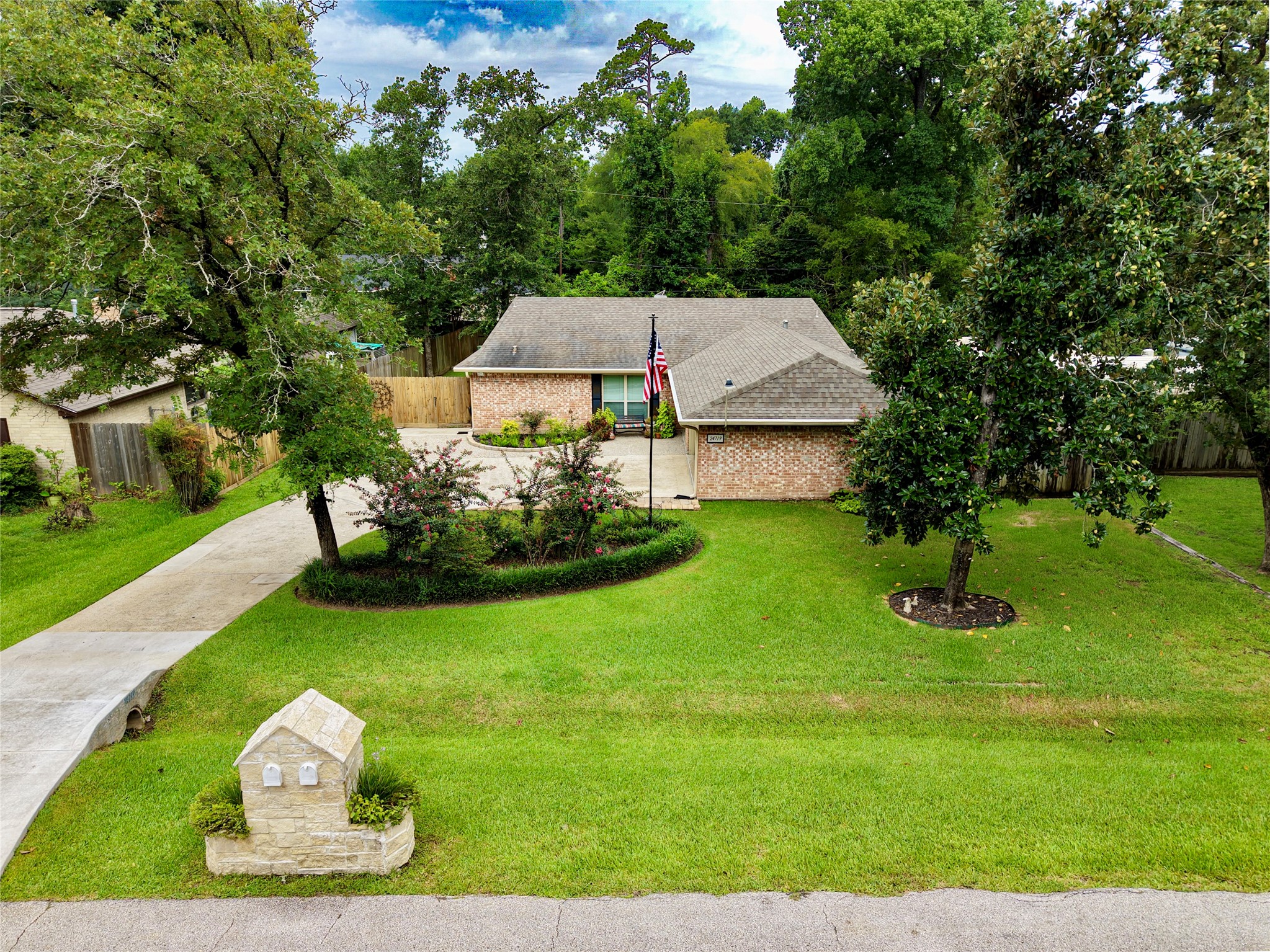 24719 Wilderness Road Spring, TX 77380 - Photo 2 of 42 Street view of house with lush landscaping, stone mailbox, and mature trees.
