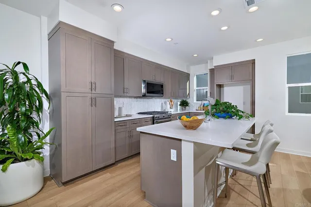 a kitchen with stainless steel appliances a table and chairs in it