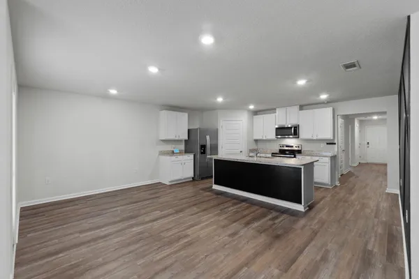 a large kitchen with kitchen island a sink wooden floor and stainless steel appliances
