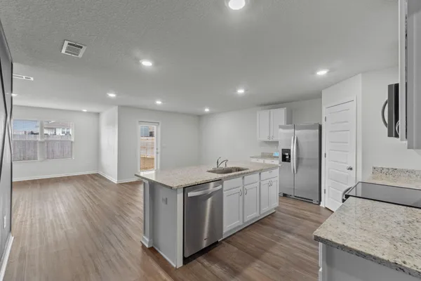 a large kitchen with stainless steel appliances granite countertop a large counter top and a stove with wooden floors