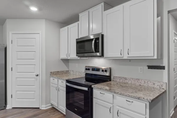 a kitchen with stainless steel appliances granite countertop white cabinets and a stove top oven