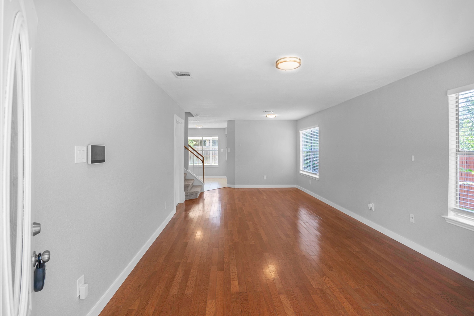 800 Smoke Signal Pass Pflugerville, TX 78660 - Photo 29 of 40 Rich hardwood floors flow through this sun-drenched living space, leading to a visible staircase.