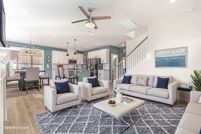 a living room with furniture kitchen view and a chandelier