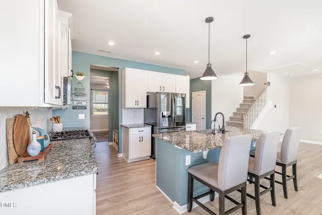 a kitchen with stainless steel appliances granite countertop a kitchen island a stove a sink a dining table and chairs