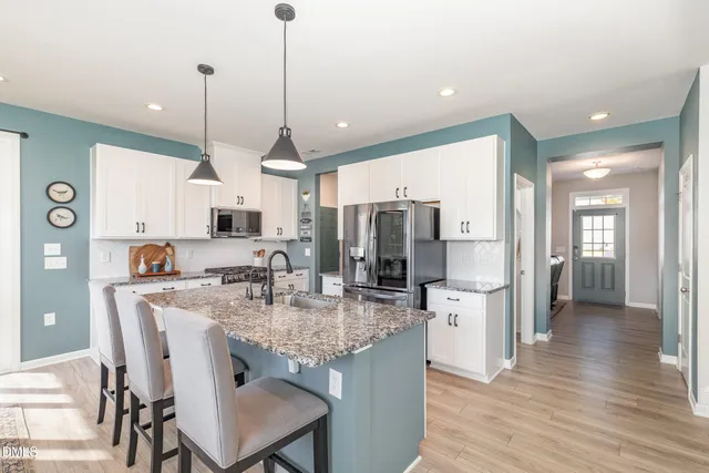 a kitchen with stainless steel appliances kitchen island granite countertop a stove a refrigerator a oven a sink with a dining table and chairs