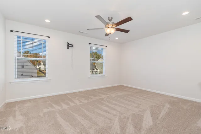 an empty room with windows and fan