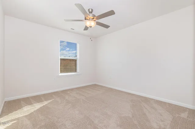 an empty room with a window and a fan