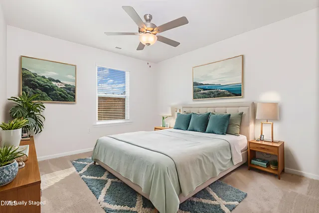a bedroom with a bed painting on wall and a potted plant
