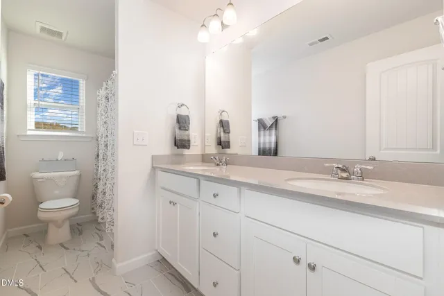 a bathroom with a granite countertop sink a toilet and a mirror