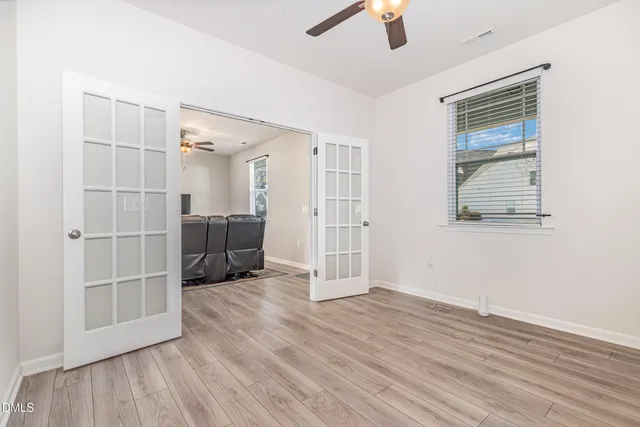 an empty room with wooden floor cabinet and windows