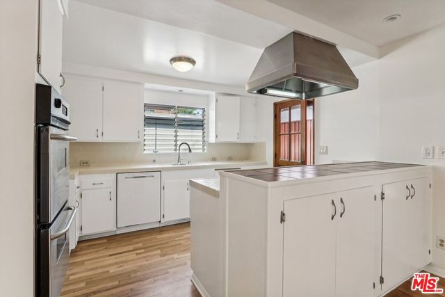 a kitchen with granite countertop a sink stainless steel appliances and white cabinets