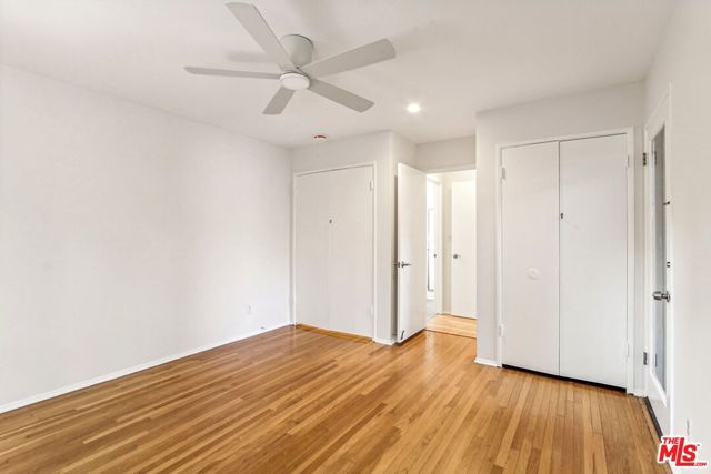 an empty room with wooden floor chandelier fan and windows