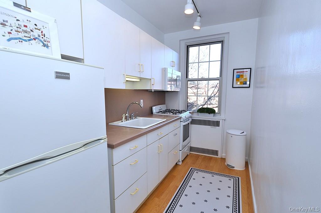 253 Garth Road, Unit 6J Scarsdale, NY 10583 - Photo 9 of 41 Kitchen has a range, microwave, refrigerator and a window for ventilation and natural light.