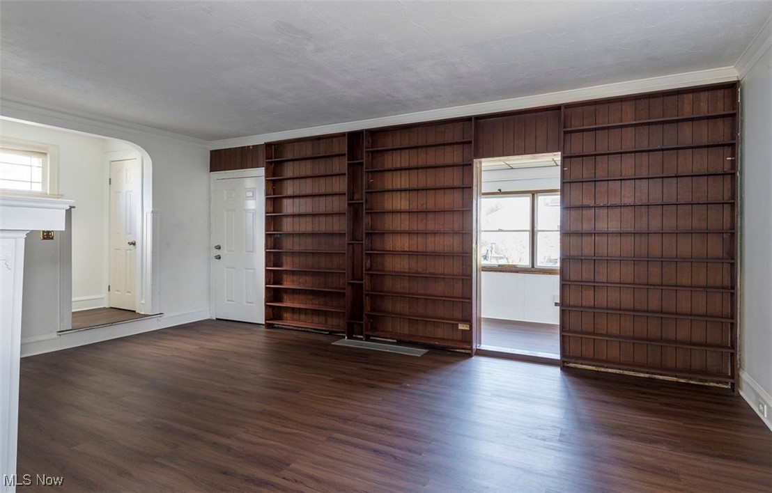 17710 Crestland Road Cleveland, OH 44119 - Photo 6 of 28 Spare room featuring dark wood-type flooring, arched walkways, and crown molding