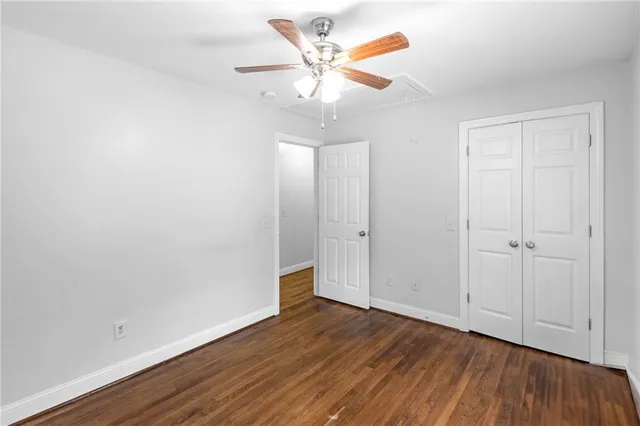 an empty room with wooden floor and a ceiling fan